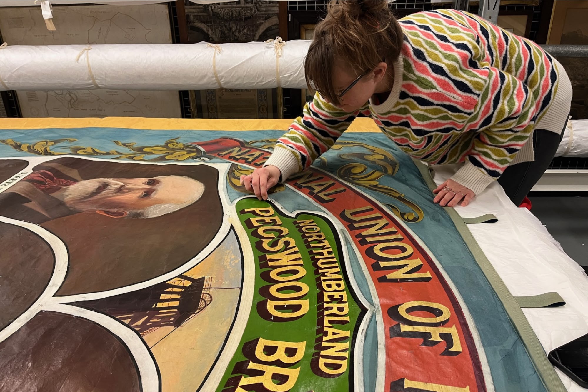 Woman works to restore a large canvas poster